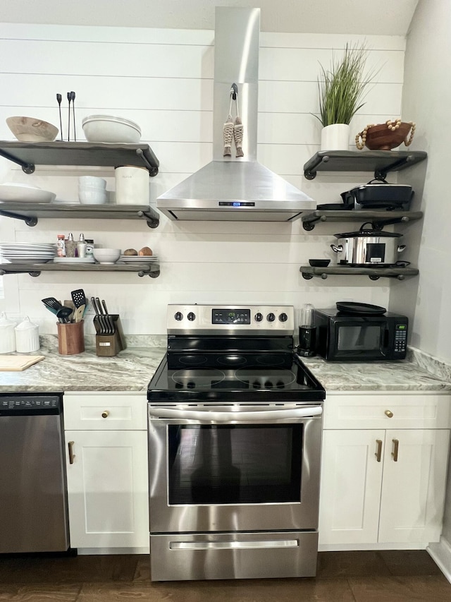 kitchen with wall chimney exhaust hood, appliances with stainless steel finishes, light stone counters, and white cabinets