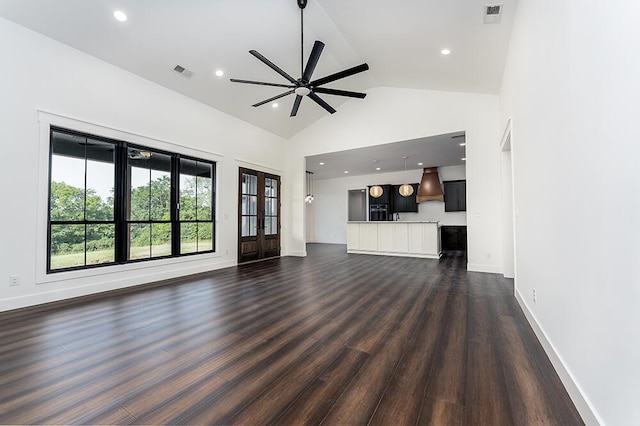 unfurnished living room featuring high vaulted ceiling, dark hardwood / wood-style floors, ceiling fan, and french doors