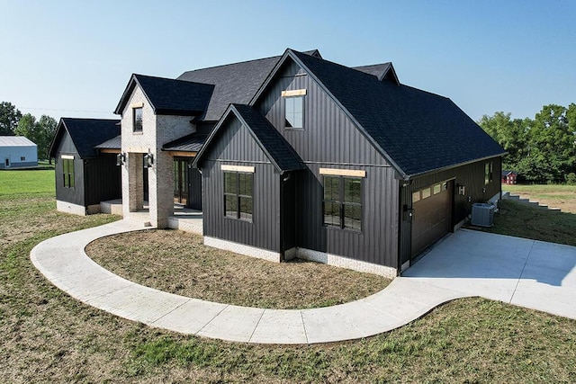 view of front of home with cooling unit, a garage, and a front lawn