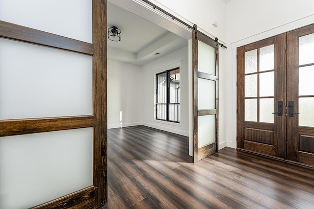 entryway featuring a barn door, a tray ceiling, dark hardwood / wood-style floors, and french doors