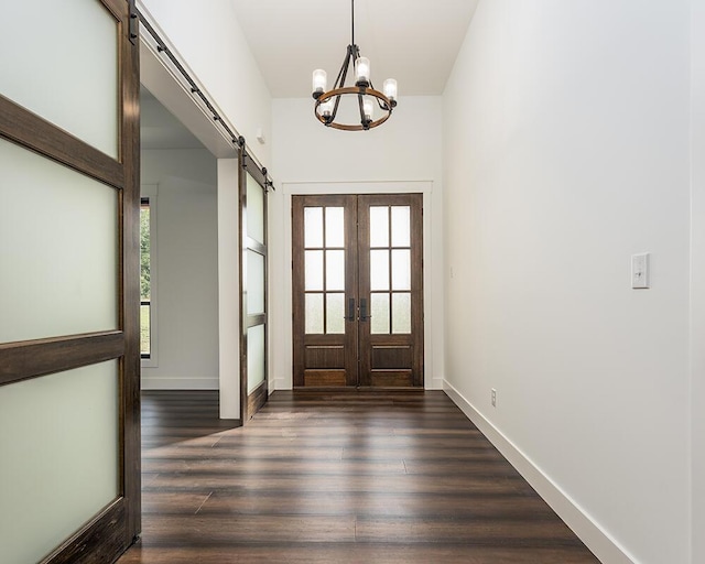 entrance foyer featuring a barn door, an inviting chandelier, dark hardwood / wood-style flooring, and french doors