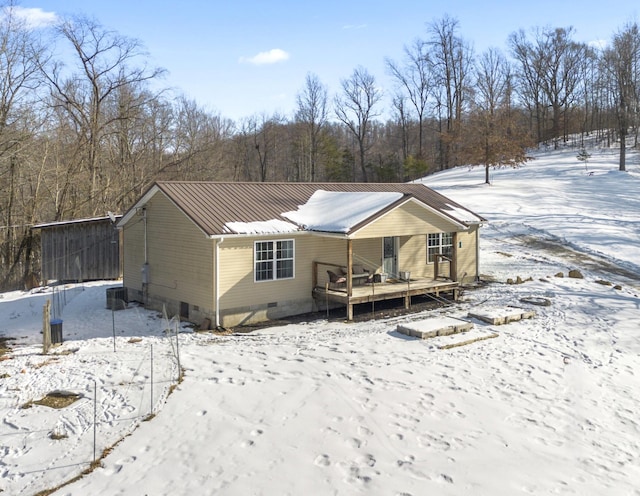 snow covered rear of property featuring central AC and a deck