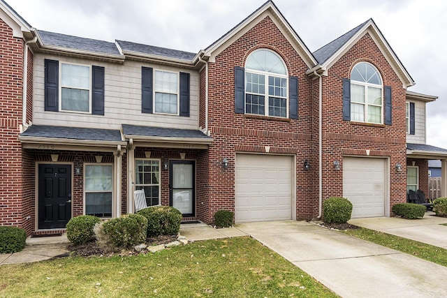 multi unit property featuring a shingled roof, brick siding, driveway, and an attached garage