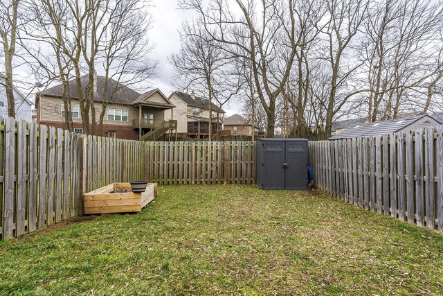 view of yard featuring a storage shed, a fenced backyard, and an outbuilding