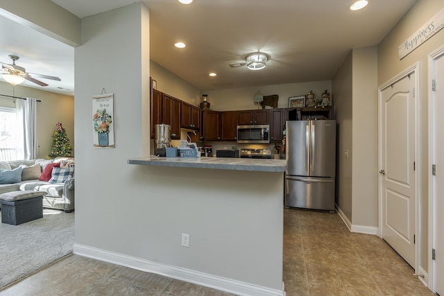 kitchen featuring light tile patterned floors, stainless steel appliances, kitchen peninsula, and ceiling fan