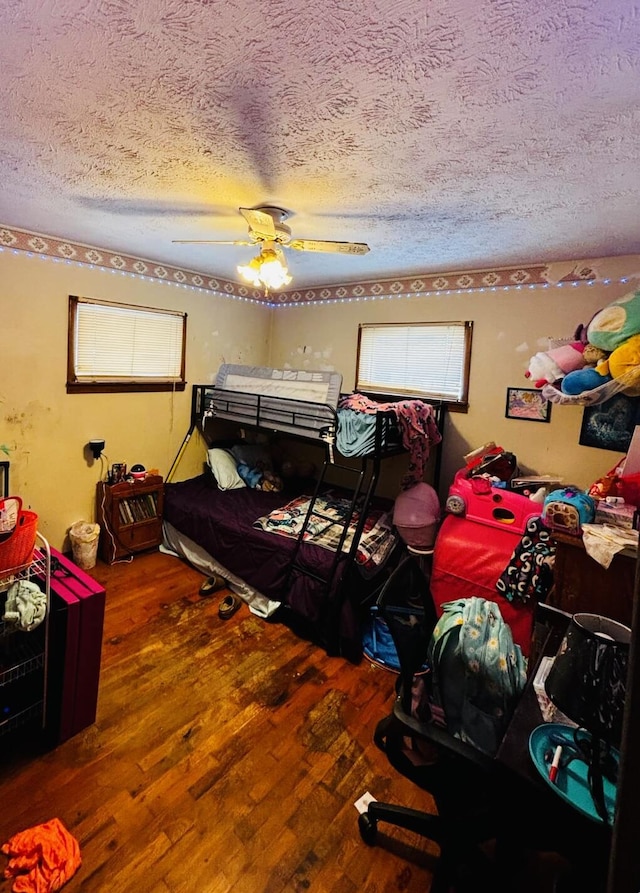 bedroom with hardwood / wood-style flooring, ceiling fan, and a textured ceiling