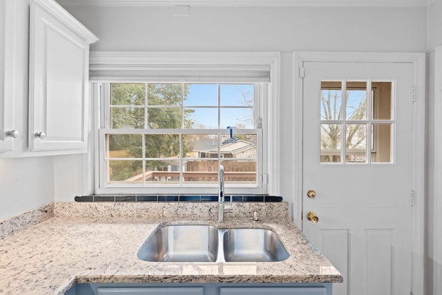 kitchen with sink, white cabinets, and light stone counters