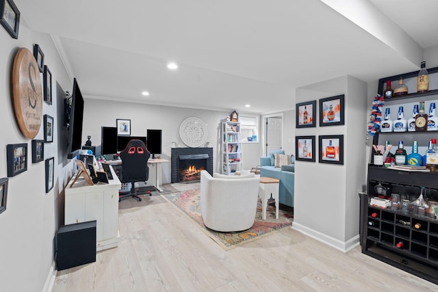 home office with crown molding, a fireplace, and light hardwood / wood-style floors