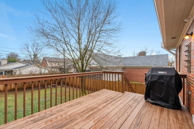 wooden terrace featuring area for grilling and a yard