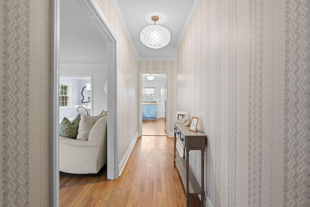 hall featuring ornamental molding, a chandelier, and light hardwood / wood-style flooring