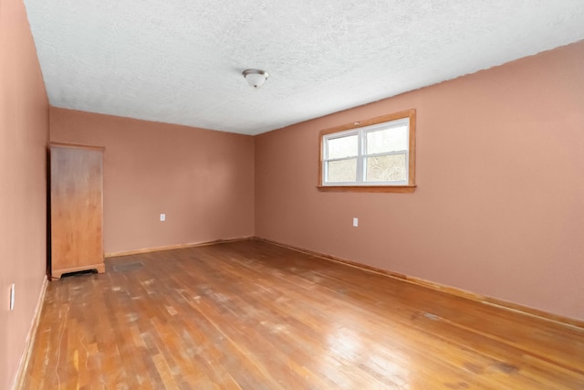 empty room with hardwood / wood-style floors and a textured ceiling