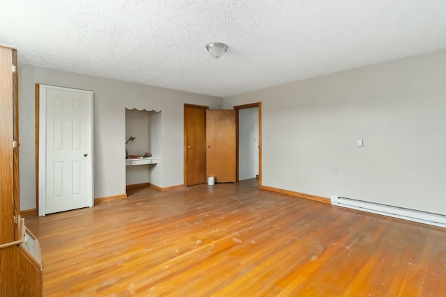 unfurnished bedroom with hardwood / wood-style floors, a baseboard radiator, and a textured ceiling