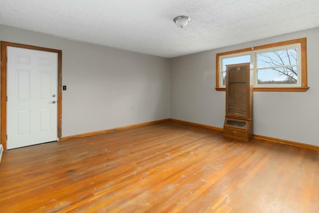 empty room with light hardwood / wood-style floors and a textured ceiling