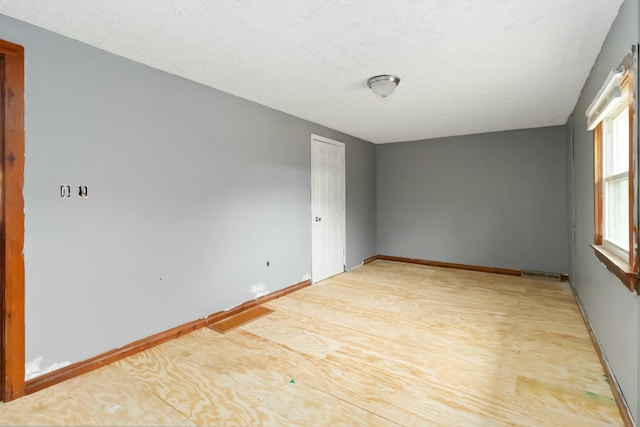 spare room with a textured ceiling and light hardwood / wood-style flooring