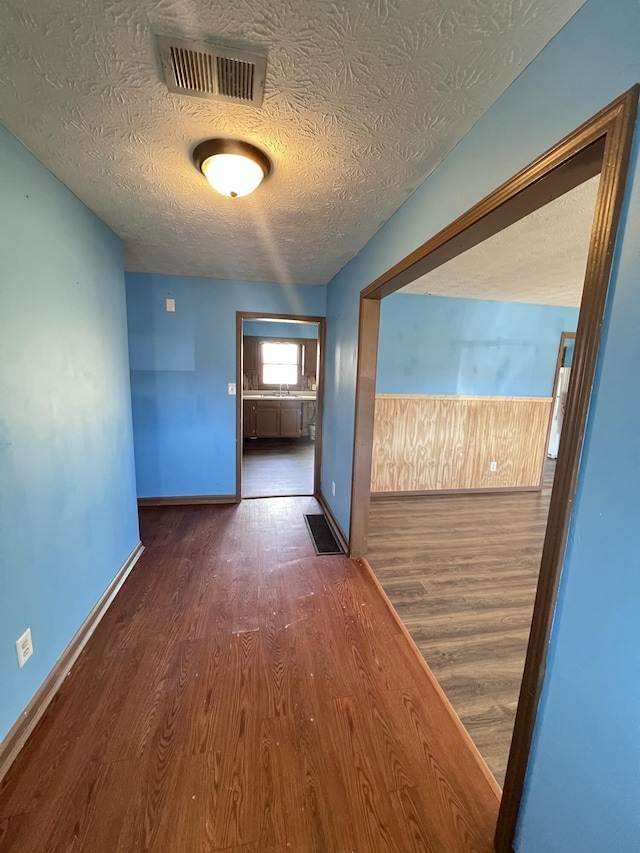 hallway with dark wood-type flooring and a textured ceiling