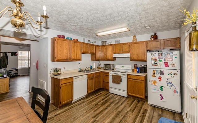 kitchen with sink, hanging light fixtures, white appliances, and dark hardwood / wood-style floors