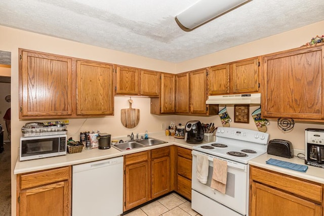 kitchen featuring sink, white appliances, light tile patterned floors, and a textured ceiling