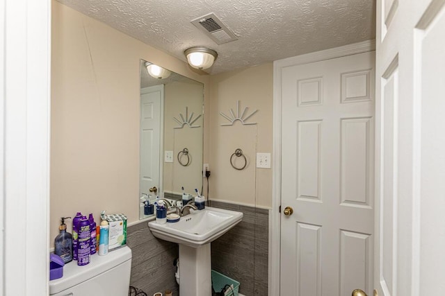 bathroom with sink, a textured ceiling, and toilet