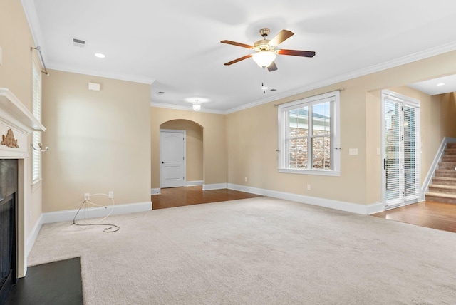 unfurnished living room featuring ceiling fan, ornamental molding, and carpet flooring