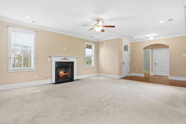 unfurnished living room with crown molding, ceiling fan, and light carpet