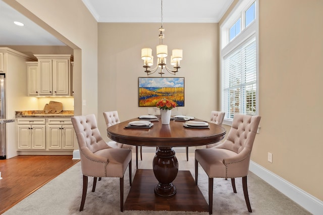 dining area with ornamental molding, an inviting chandelier, and light hardwood / wood-style flooring