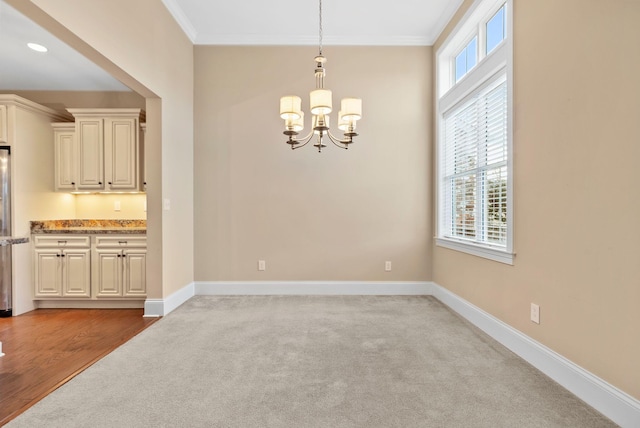 unfurnished dining area with crown molding, a chandelier, and carpet