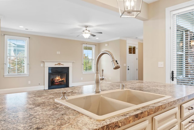 kitchen featuring sink, ornamental molding, and ceiling fan