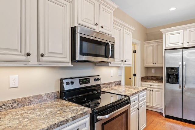 kitchen featuring light stone counters, appliances with stainless steel finishes, and white cabinets