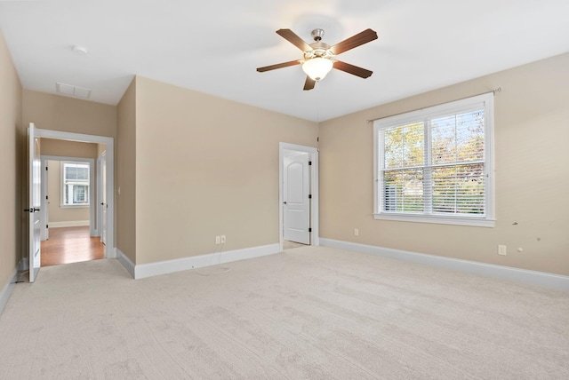 unfurnished room featuring plenty of natural light, light carpet, and ceiling fan