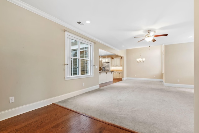 unfurnished living room with crown molding, wood-type flooring, and ceiling fan with notable chandelier