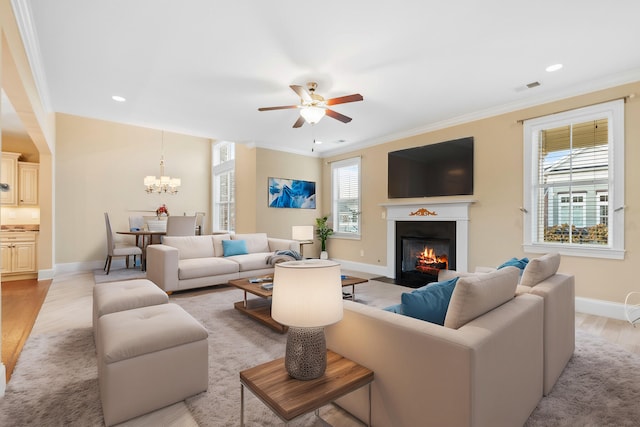 living room featuring crown molding, ceiling fan with notable chandelier, and light wood-type flooring