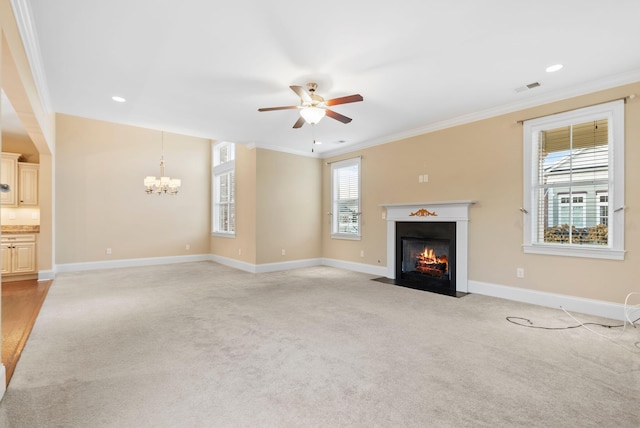 unfurnished living room with ornamental molding, ceiling fan with notable chandelier, and light colored carpet