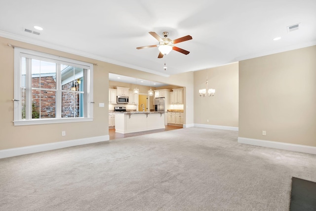 unfurnished living room featuring ceiling fan with notable chandelier, ornamental molding, and light colored carpet