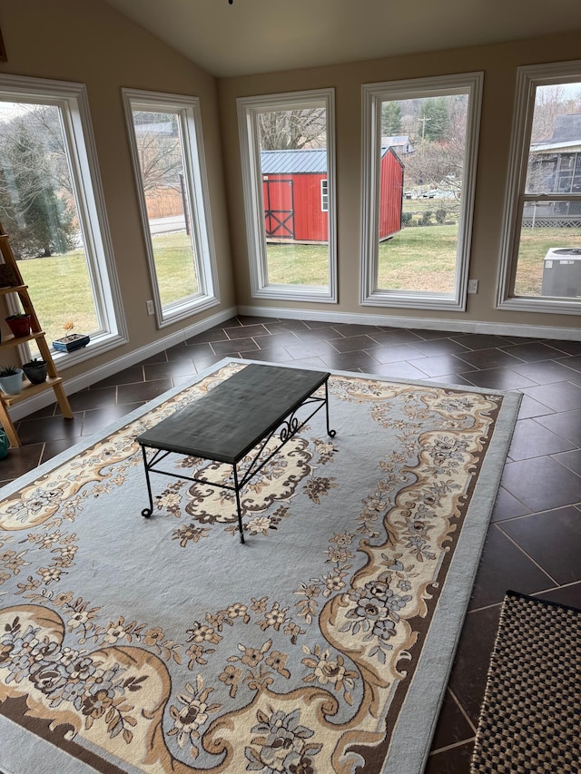 unfurnished living room featuring dark tile patterned flooring and vaulted ceiling