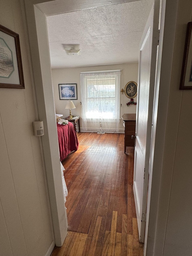 hall featuring dark wood-type flooring and a textured ceiling