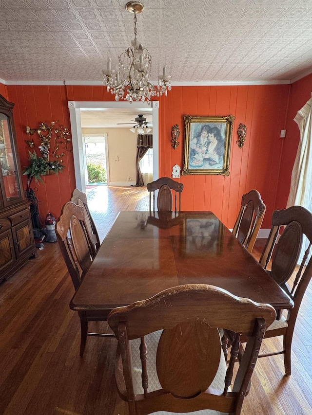 dining space featuring ceiling fan with notable chandelier, wood-type flooring, and ornamental molding