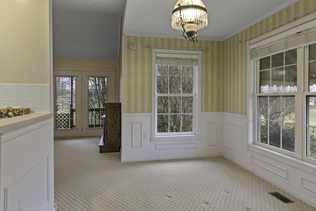 interior space with a notable chandelier, a wealth of natural light, carpet floors, and ornamental molding