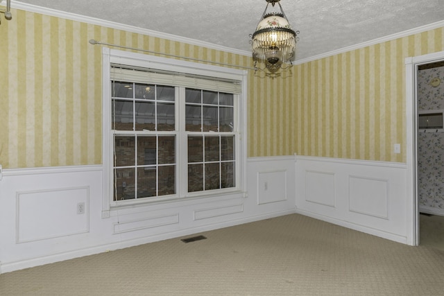 carpeted empty room featuring an inviting chandelier, ornamental molding, and a textured ceiling