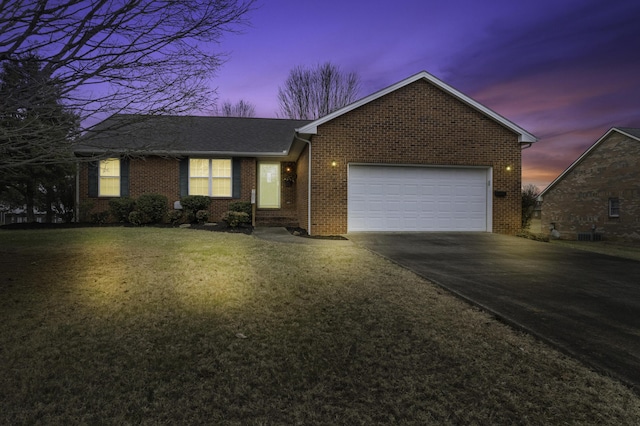 ranch-style home featuring a garage and a yard