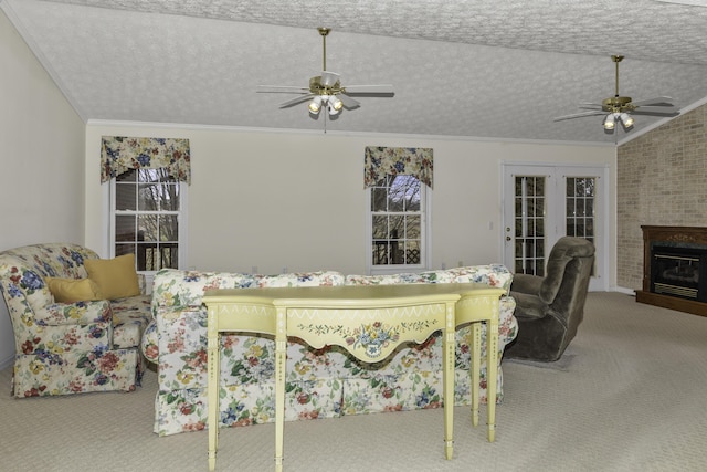 carpeted living room with lofted ceiling, a textured ceiling, a large fireplace, and ceiling fan