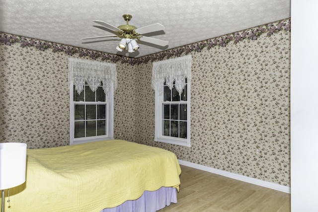 bedroom with ceiling fan, hardwood / wood-style floors, and a textured ceiling