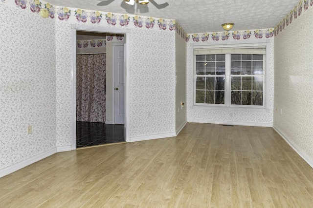 unfurnished room featuring ceiling fan, hardwood / wood-style floors, and a textured ceiling