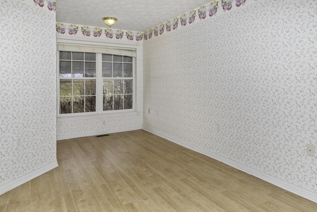 unfurnished room featuring hardwood / wood-style flooring and a textured ceiling