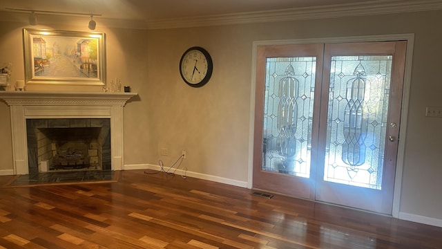 foyer entrance featuring ornamental molding, dark wood-type flooring, and a fireplace