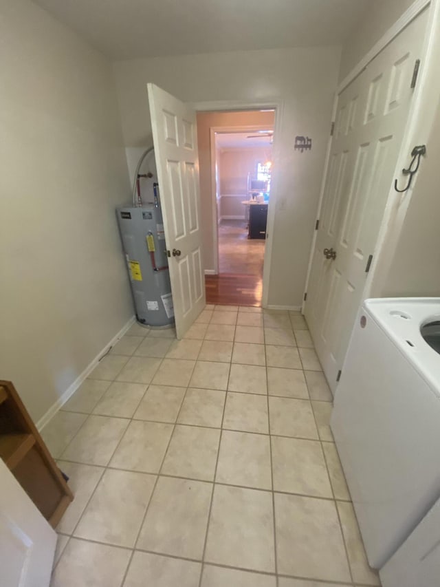 clothes washing area featuring water heater and light tile patterned floors