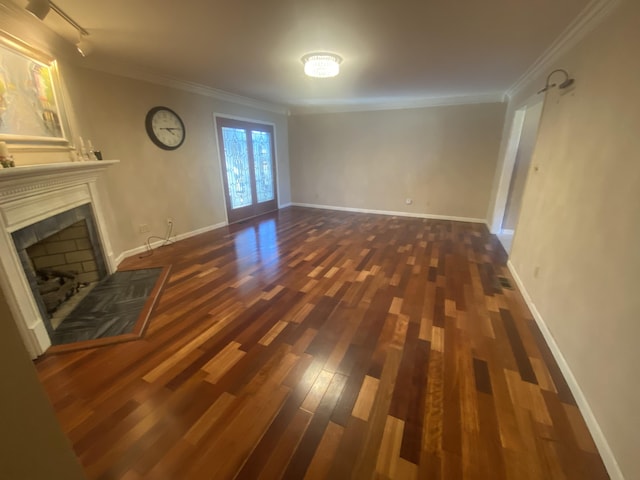 unfurnished living room with dark wood-type flooring, track lighting, ornamental molding, and a tiled fireplace