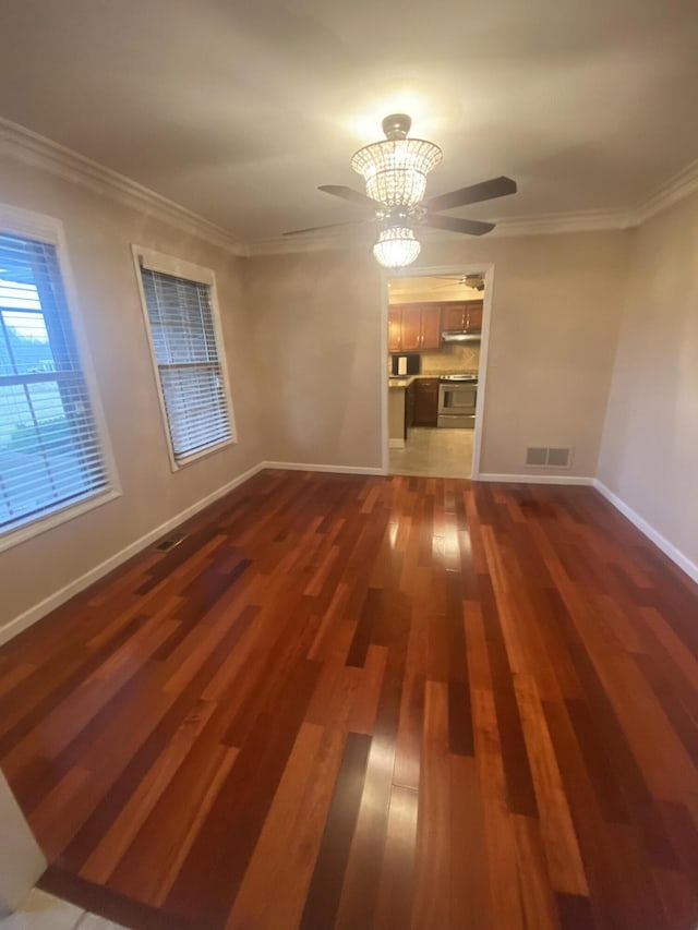 empty room featuring dark wood-type flooring, ornamental molding, and ceiling fan