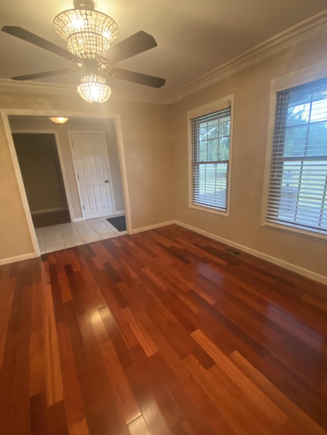 empty room featuring ceiling fan, hardwood / wood-style flooring, ornamental molding, and a healthy amount of sunlight