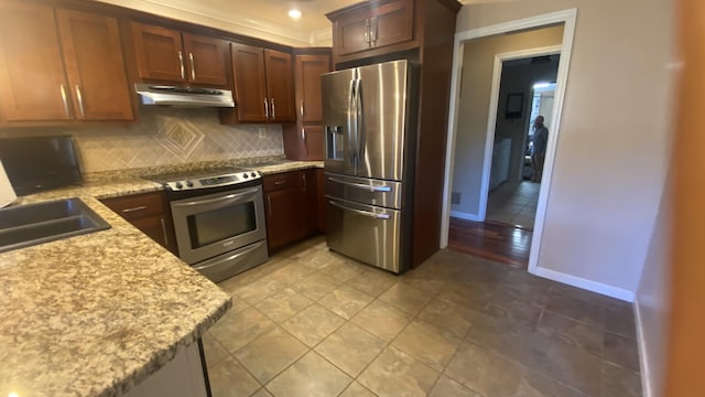 kitchen with light stone counters, sink, decorative backsplash, and stainless steel appliances