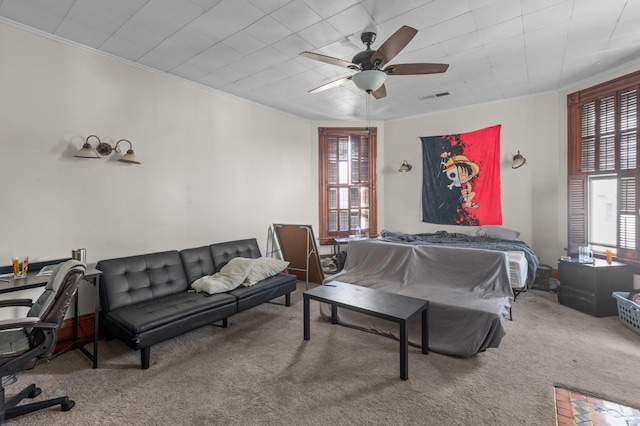 carpeted bedroom with ornamental molding and ceiling fan